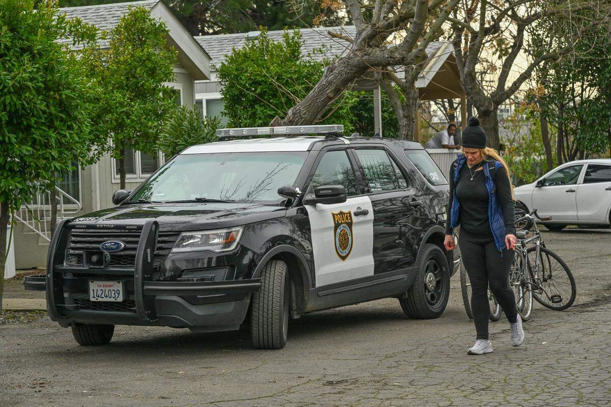 Jessica Rose walks past her bicycles and a Sacramento police vehicle after throwing some of her belongings in the trash while being evicted with her 11-year old daughter and husband in February. She was allowed to store a few items on the property for three weeks until she could save enough money to get a storage unit.