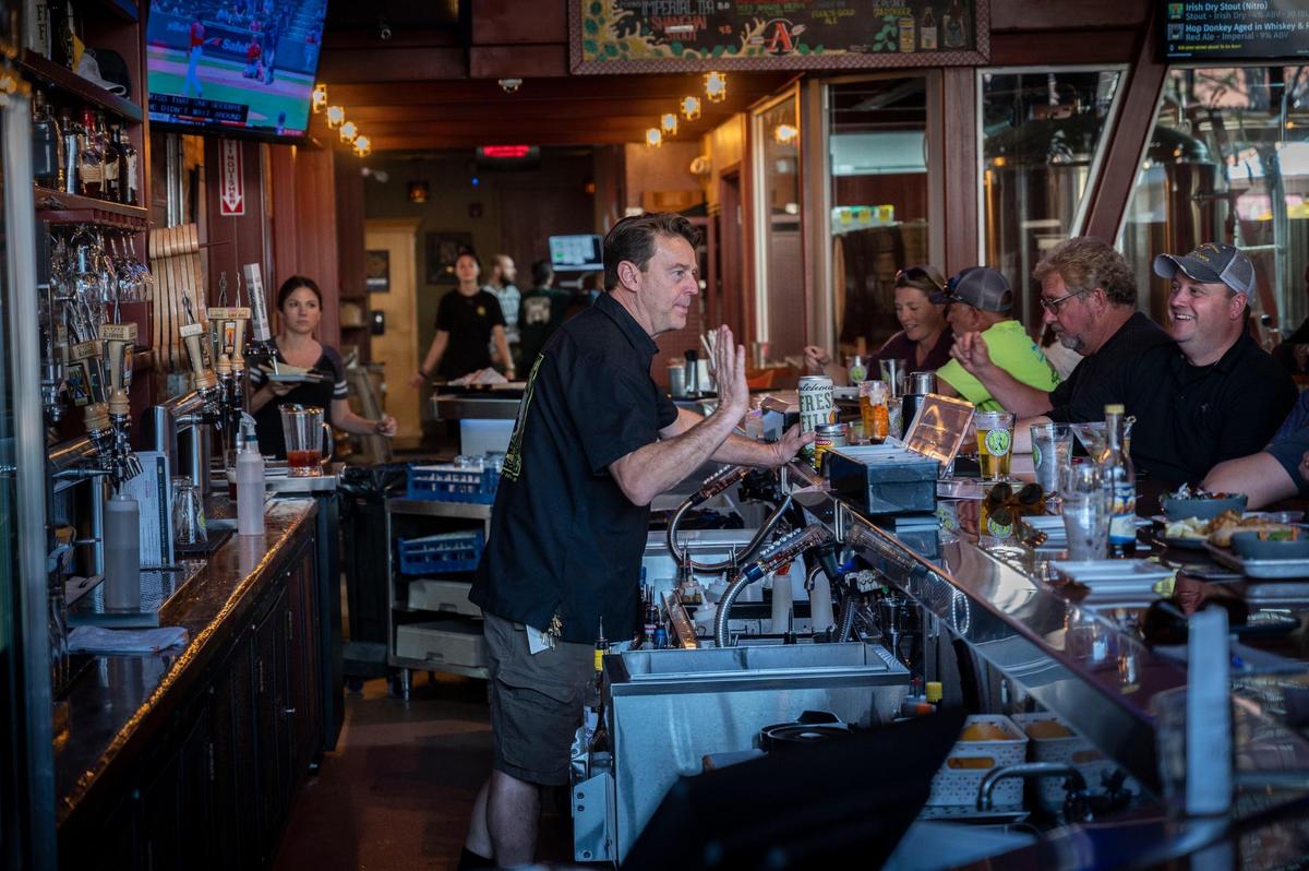 Auburn Alehouse brewmaster Brian Ford waves while talking with customers at the bar on April 5. He and his wife Lisa Ford have developed a devoted group of followers since opening in 2007.