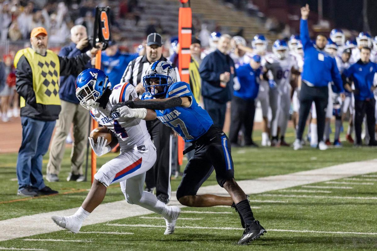 Folsom Bulldogs running back Toure Hendrick (4) runs the ball to the 4-yard line before being pushed out of bounds by Rocklin Thunder defensive back Nathan Kent (17) during the third quarter of the Sac-Joaquin Section Division I championship game at Hughes Stadium in Sacramento on Friday. The Bulldogs won 20-3.