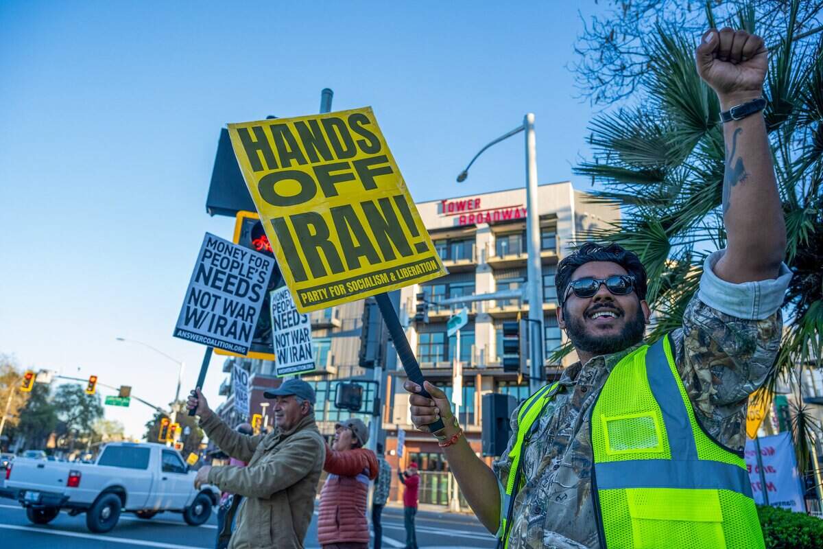Kunaal Kumar holds up his fist at the corner of Land Park Drive and Broadway in Sacramento on Monday while demonstrating against the U.S.-Israel war with Iran.