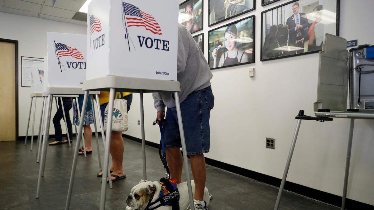Tom Brezinski, right, votes with his service dog Suzie at his feet at the Los Angeles County Registrar of Voters office Tuesday in Norwalk, Calif. The general election takes place on Nov. 6.