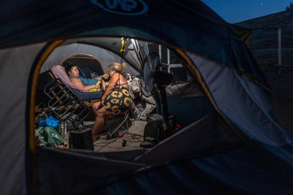Late at night Holly Porter, 40, sits in her hospital bed alongside her pit bull Felicia while she talks in October to her mother Deborah Casillas, who lived in a tent nearby along the American River at the time. Porter, who been told she has a few years to live, now lives in an encampment in North Sacramento.