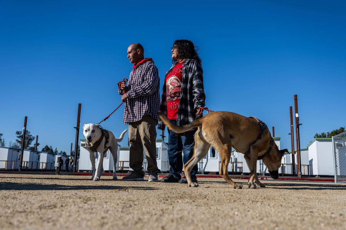 Bartholomew Keller and Natalia Sanchez, who share a cabin at the new Stockton Boulevard Safe Stay Community, walk their dogs Twoface and Lala on Wednesday at the county homeless housing facility in south Sacramento that opened last month.