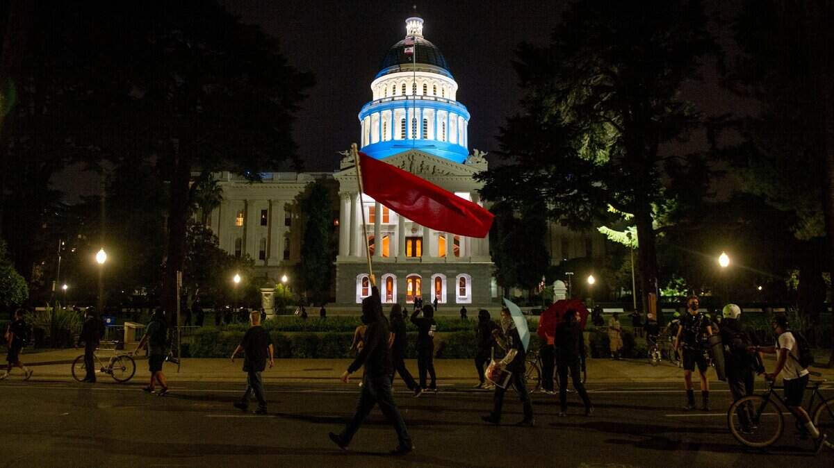 A group of demonstrators march in front of the California State Capitol Building on Friday, Aug. 28, 2020, in downtown Sacramento. The second night of protests for “Solidarity With Kenosha” started at Cesar E. Chavez Plaza, and left downtown buildings with broken windows and graffiti.