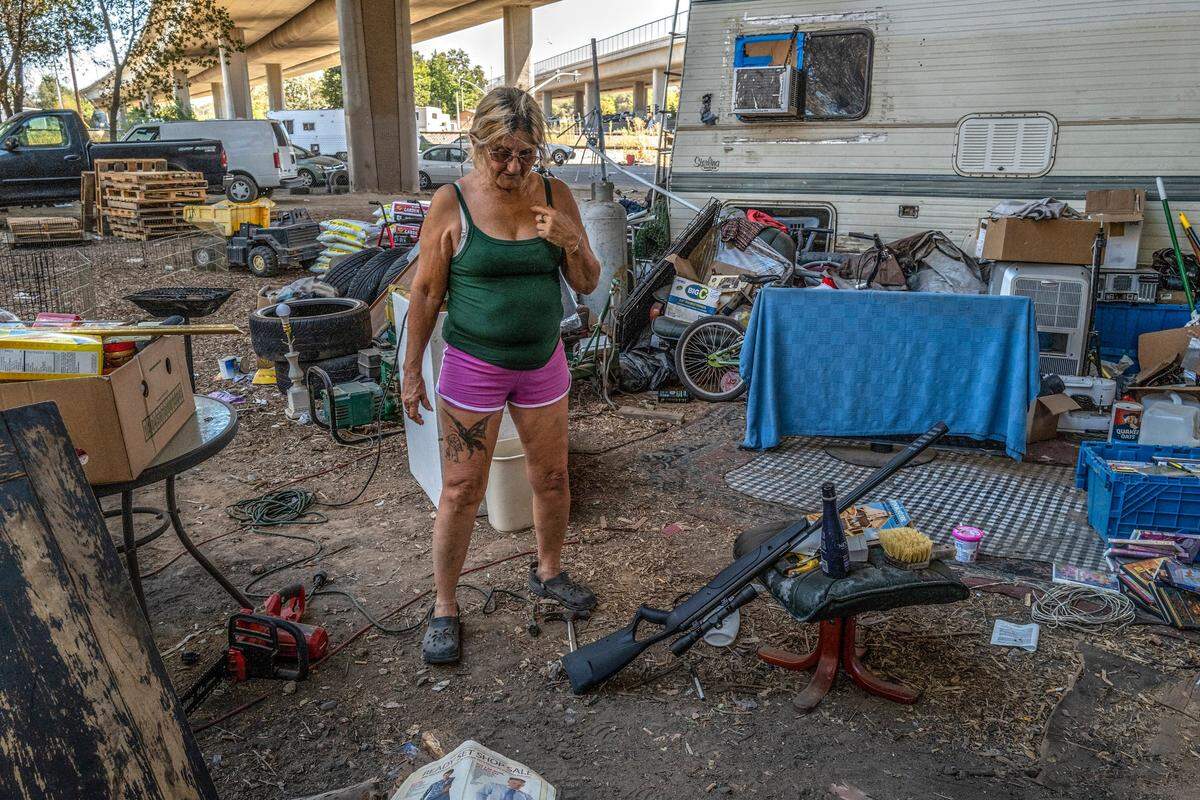 Gwen Mayse, 62, stands on Aug. 25 near the BB gun she said she uses to kill rats while living in a tent underneath a freeway in north Sacramento. Her daughter’s trailer is parked in the background. She said she didn’t have to worry about rats when she lived at the homeless encampment near Howe Avenue and Fair Oaks Boulevard.
