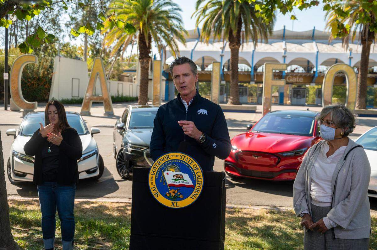 California Gov. Gavin Newsom stands in front of four electric cars at Cal Expo in Sacramento in 2020 to announce an executive order requiring all new passenger vehicles sold in the state to be zero-emission by 2035, a move the governor says would achieve a significant reduction in greenhouse gas emissions.