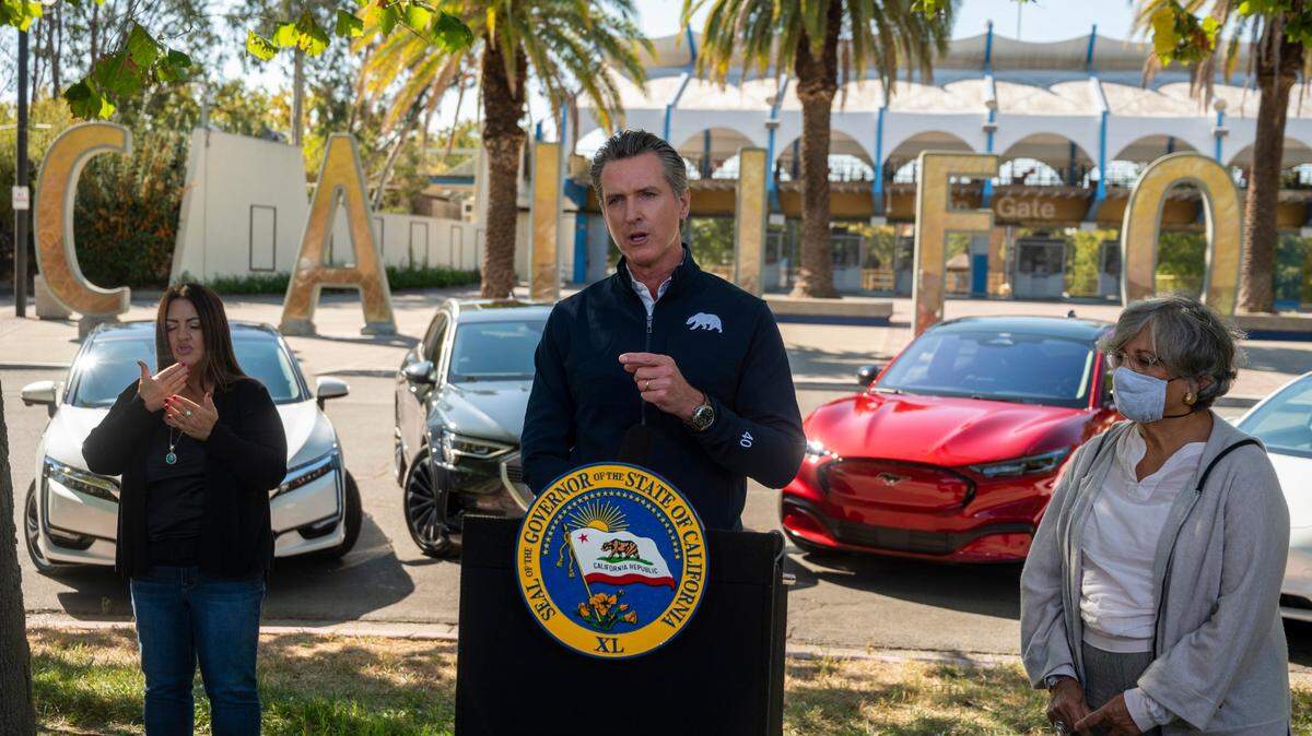 Gov. Gavin Newsom stands in front of four electric cars at Cal Expo in Sacramento in 2020 to announce an executive order requiring all new passenger vehicles sold in the state to be zero-emission by 2035.