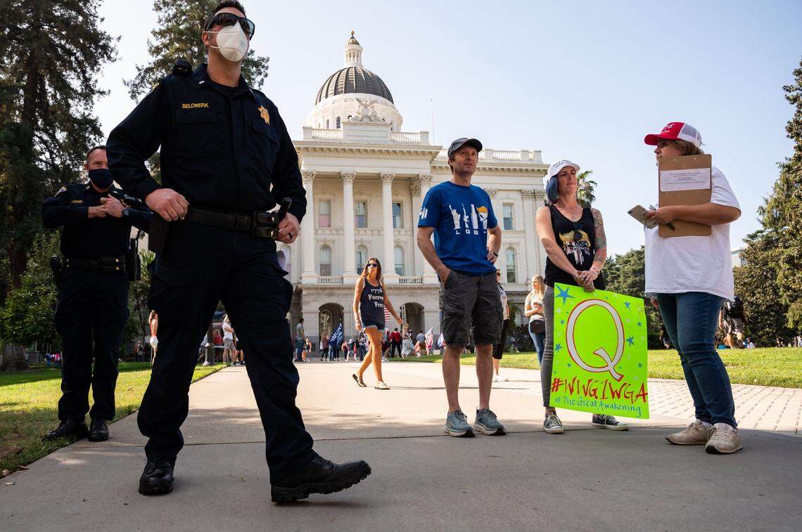 Kaela McGuire, of Fair Oaks, holds a sign supporting the QAnon movement while talking with El Dorado Hills resident and “Recall Gavin Newsom” campaigner Kelley Nalewaja, right, during The Freedom Tour USA event at the state Capitol on Saturday, Sept. 19, 2020. The QAnon movement, a collection of baseless conspiracy theories aimed at exposing a supposed deep-state cabal of pedophiles, has recently gained traction with some celebrities and a swath of congressional candidates. “I don’t know that the mainstream media wants us to do our own research, and counter the narrative that they’re fighting so hard for us to believe,” said McGuire, talking about why she’s drawn to QAnon.