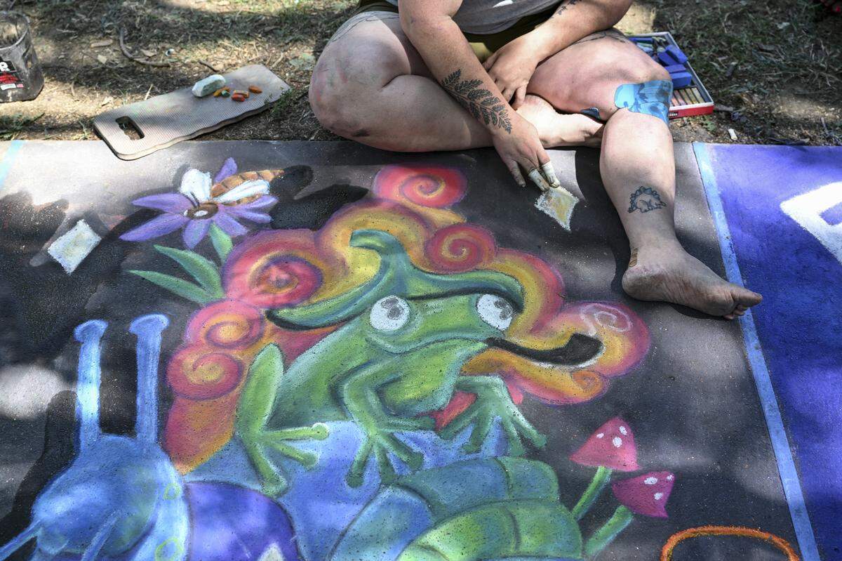 Artist Kathleen Bowen, of Salt Lake City, works on a chalk art piece of a frog and a snail during Chalk It Up art festival at Fremont Park in Sacramento on Sunday.