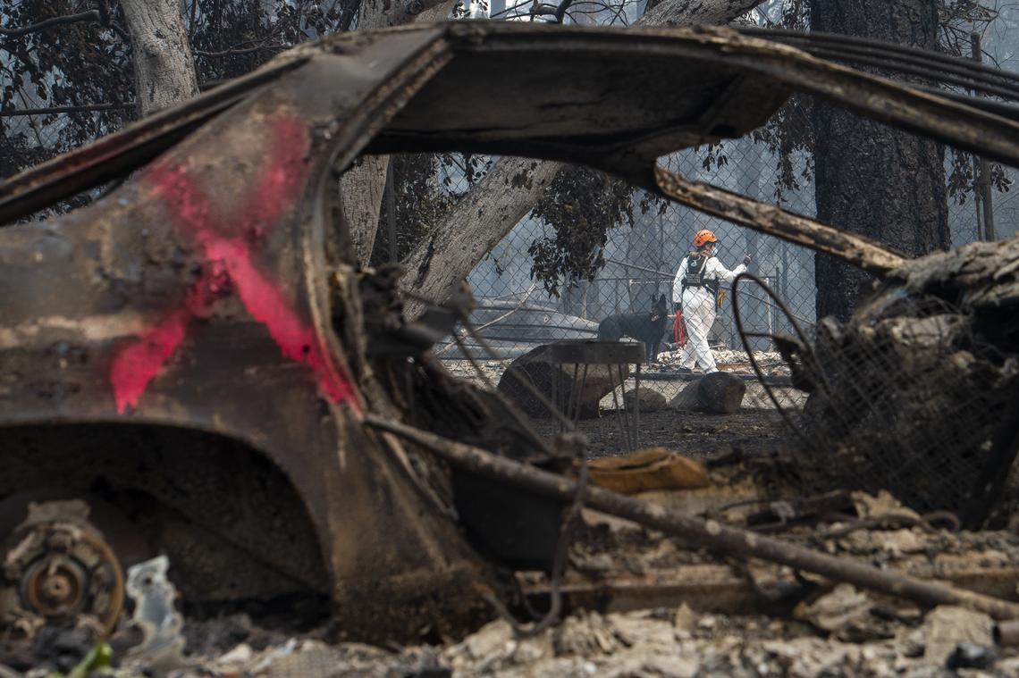 A burned vehicle is marked with a red x to show that it’s been searched as workers from the state office of Emergency Services, dressed in white hazard suits and employing dogs, sift through an area devastated by the Camp Fire in Paradise, Thursday Nov. 15, 2018.
