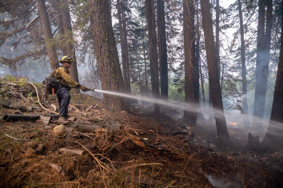 Fire crews from Santa Clara put out hot spots on Monday at Camp Sacramento in the Eldorado National Forest during the Caldor Fire. The firefighters worked through the night to protect the beloved recreation site.