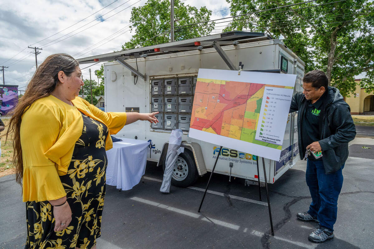 Crystal Sanchez, left, president of the Sacramento Homeless Union, and Herman Barahona of the Sacramento Environmental Coalition straighten out a chart showing heat and air quality before a Monday press conference about the opening of the Stoop Cooperative resource hub on Del Paso Boulevard in North Sacramento. The hub will use a solar-powered mobile trailer for cell phone charging.