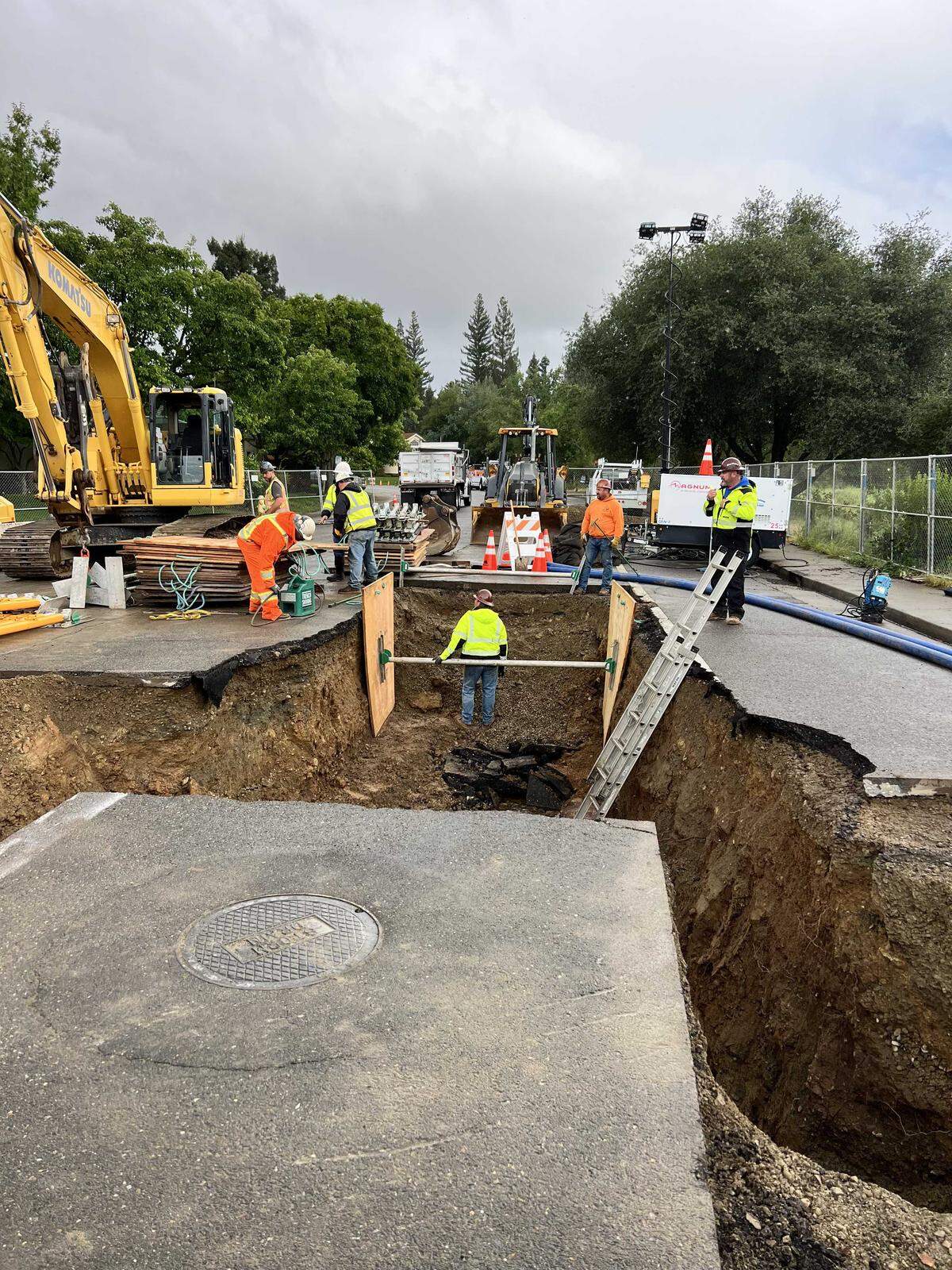 A large sinkhole blocks the intersection of Prewett and Newington drives in the Lexington Hills neighborhood of Folsom on Monday, April 13, 2026. The sinkhole opened after a series of weekend storms brought heavy rain to Northern California, prompting crews to install barriers and set up detours for residents.
