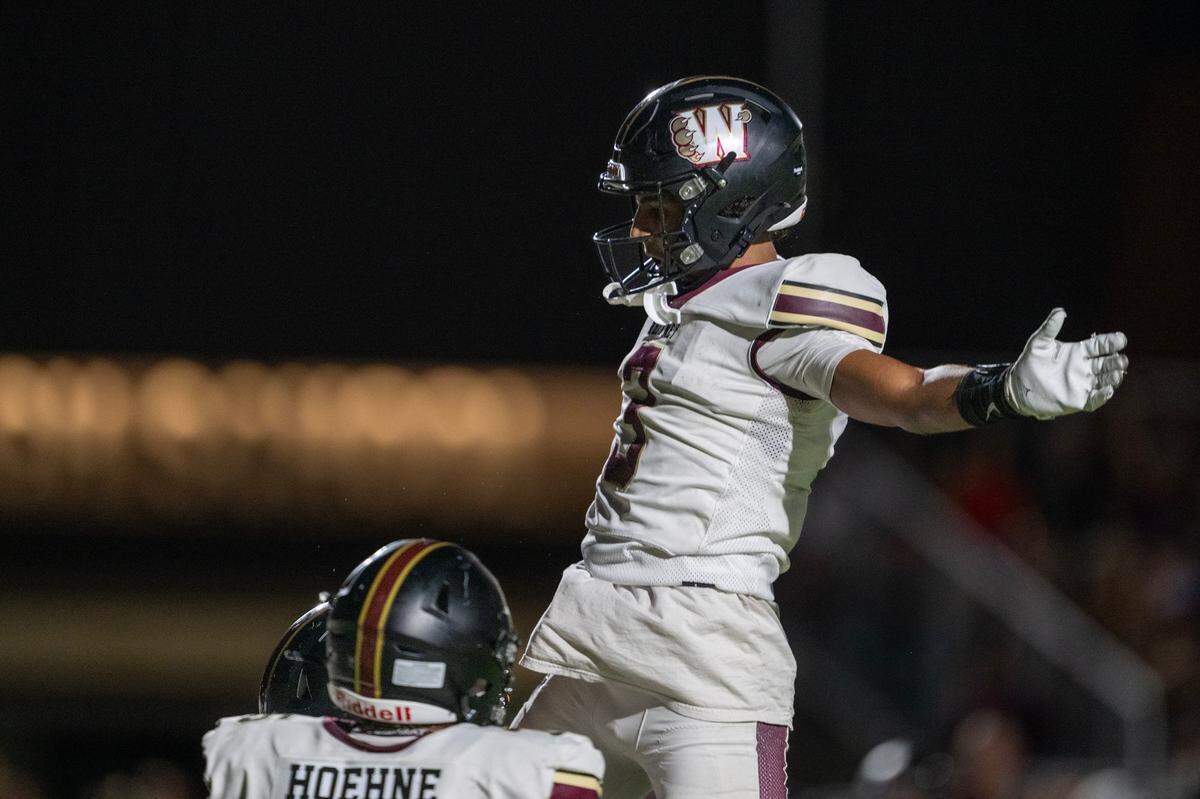 The Whitney Wildcats’ Carson Floyd (3) leaps into the air after scoring a touchdown run in the first quarter against the Twelve Bridges Raging Rhinos in 2024 at Twelve Bridges High School.