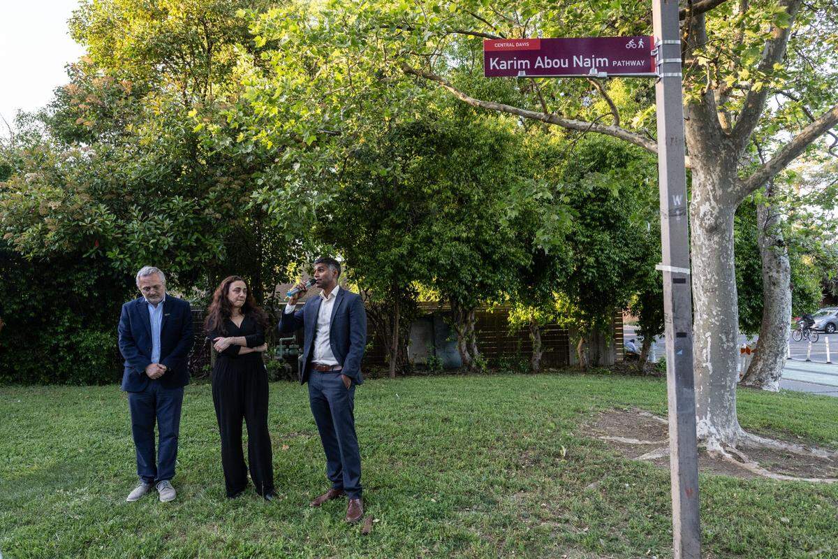 A newly unveiled sign for a bikeway bears the name of UC Davis Karim Abou Najm on Monday, the one-year anniversary of his fatal stabbing, as his father Majdi Abou Najm, left, and mother Nadine Yehya, center, stand with Davis City Councilman Bapu Vaitla.