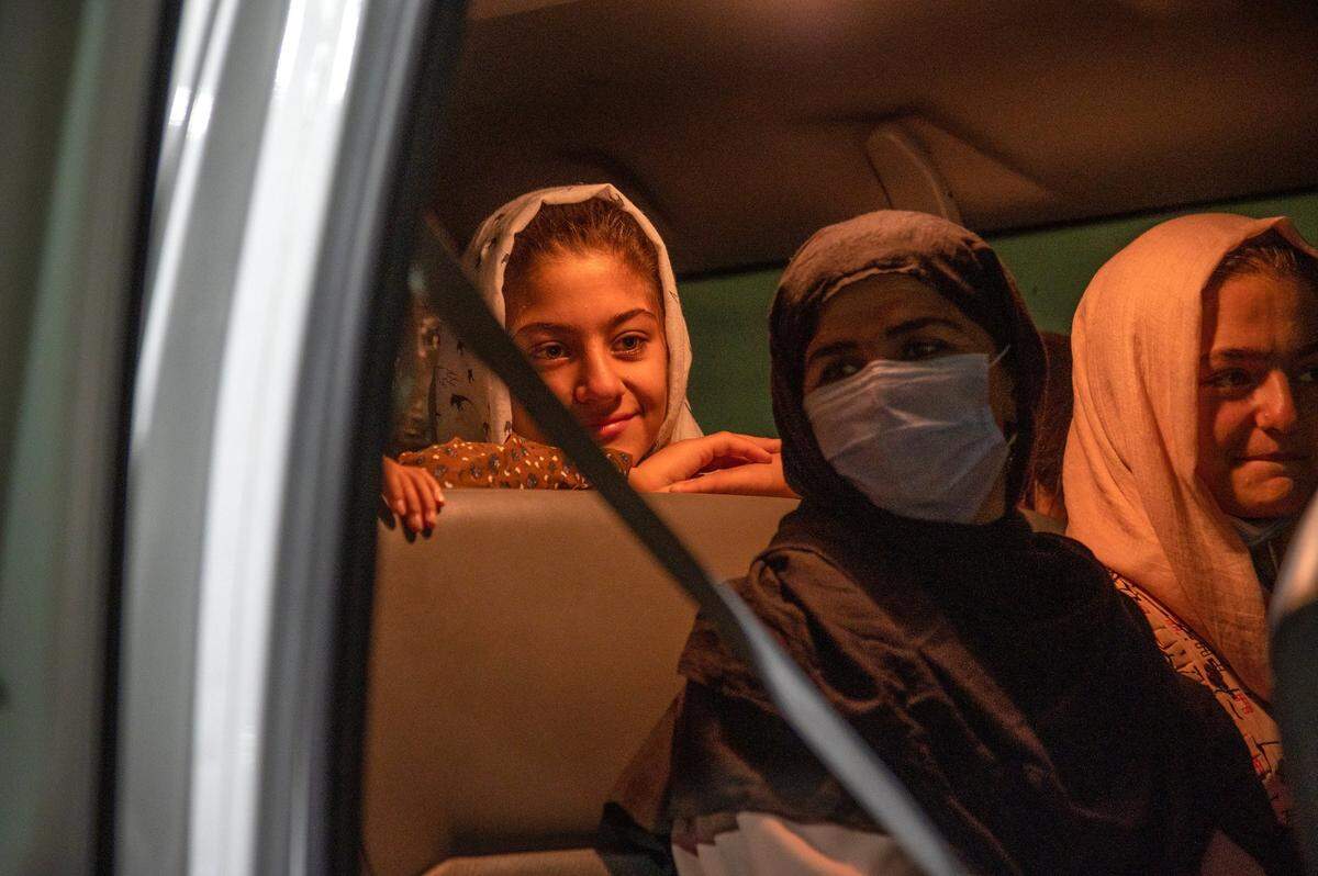 Afghan refugees Istoray, 15, left, her mother Adela, center, and sister Suraya, 18, show mixed emotions after they board a Lao Family Community Development van upon after arriving in Sacramento. The resettlement organization had less than 24 hours to prepare for the arrival of the family.