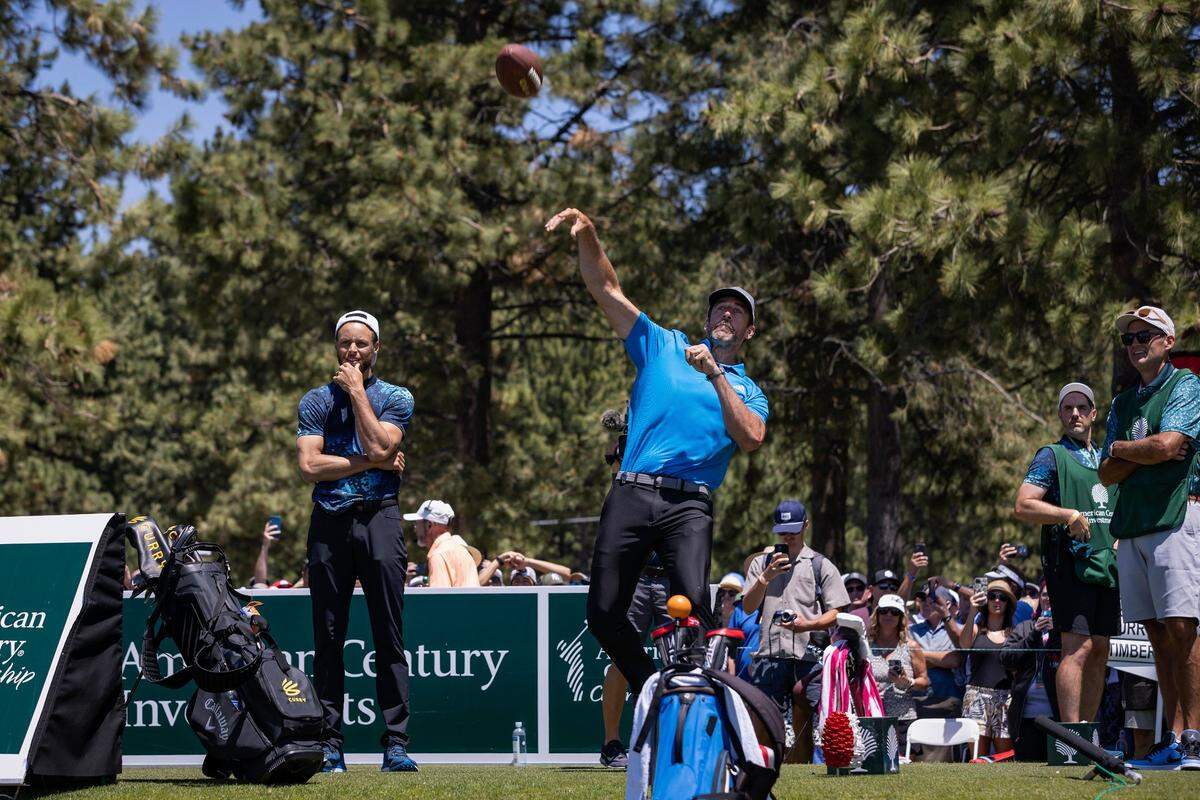 Golden State Warriors star Stephen Curry, left, watches as Green Bay Packers quarterback Aaron Rodgers throws a football to fans on the seventeenth hole during the American Century Celebrity Golf Championship Tournament at Edgewood Tahoe Golf Course in Stateline, Nev., on Sunday, July 10, 2022.
