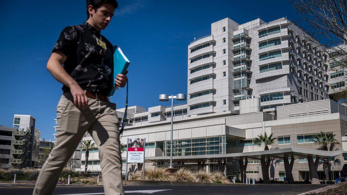 A man walks by UC Davis Medical Center in Sacramento on Thursday, Feb. 27, 2020. A patient from Solano County, who is the first confirmed case of the coronavirus in the United States of unknown origin, is being treated for coronavirus at the hospital. 