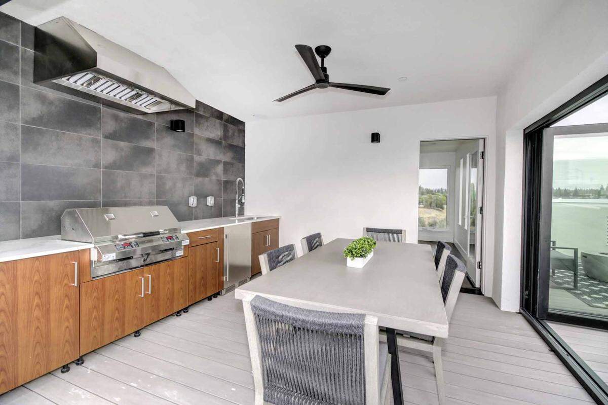 The glass doors of the covered outdoor kitchen and dining area can be opened for access to the pool.