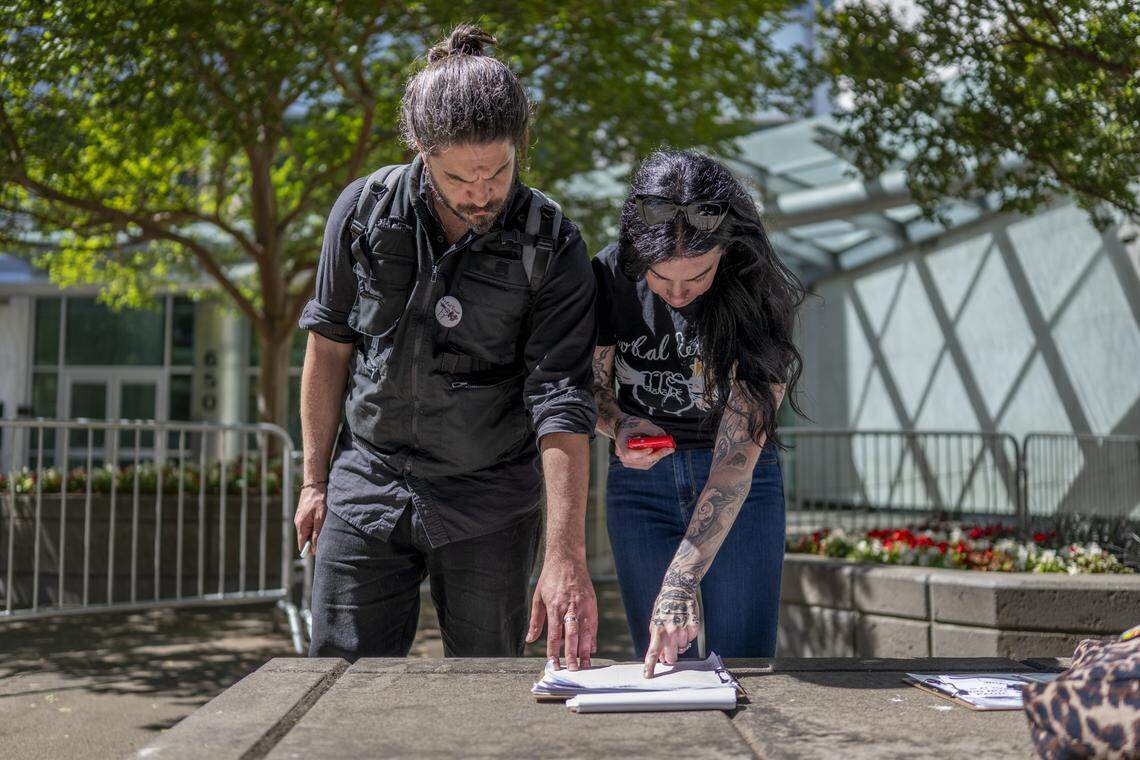 Niko Volonakis, right, and Heidi Phipps, right, review clipboards containing the information of people interacting with immigration related officials at the John E. Moss federal building in downtown Sacramento between immigration court hearings on July 22. Individuals can provide their name, immigration identification number, as well as a friend or relative's information to contact if they are detained.
