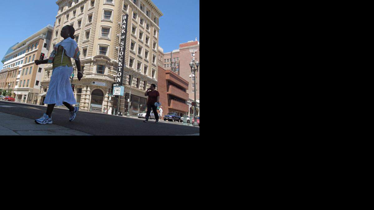 
Pedestrians cross a street near the Bank of Stockton in Stockton, Calif. 
