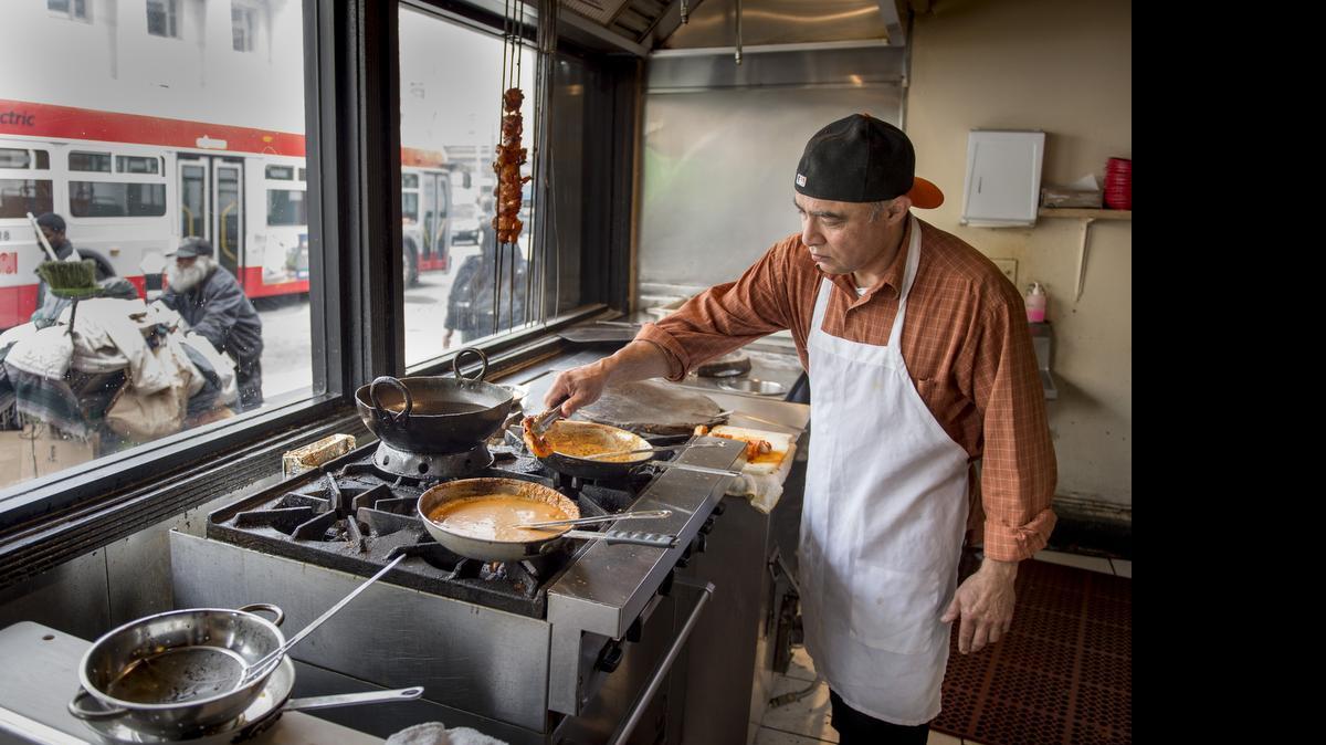 
Kitchen and restaurant helper Muhammad Seikh cooks up an order at Alhamra Restaurant in San Francisco on Friday.
