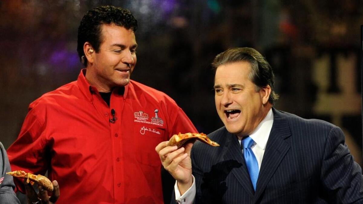 Papa John’s founder and CEO John Schnatter, left, and NFL Network analyst Steve Mariucci are seen with pizza from Schnatter’s company in 2013. Papa John’s took to Twitter on Tuesday to clarify remarks from a quarterly conference call about the NFL nearly two weeks ago.