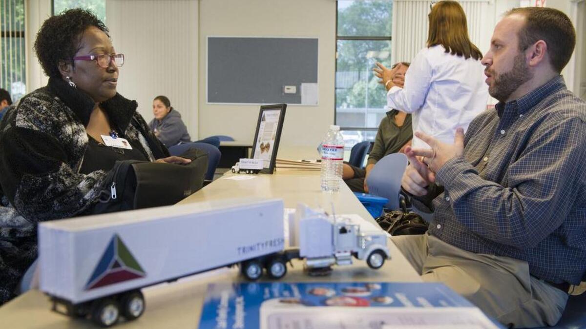 Orelia Simmons, 53, left talks David Hembree, a transportation manager with Trinity Fresh during a trucking career fair hosted by Highlands Community Charter School, Wednesday, May 20, 2015.