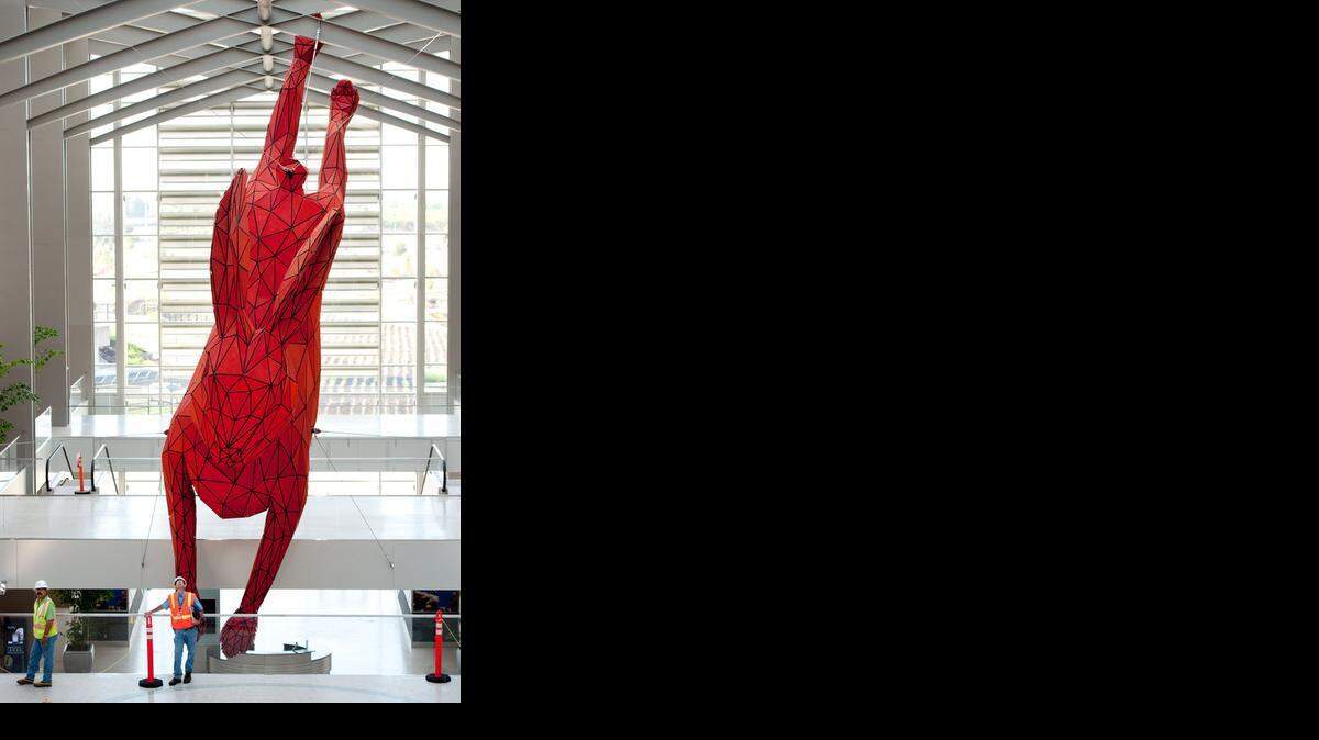
Construction workers mingle around the 56-foot-long, 15-foot diameter "Leap", a red rabbit made of steel and aluminum by Denver artist Lawrence Argent hangs from cables inside the new Terminal B at the Sacramento international Airport.
