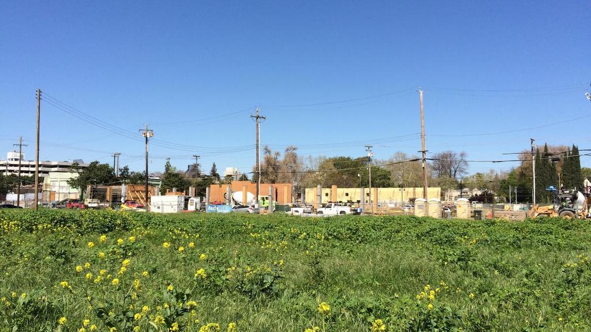 The weedy acreage eyed for a mixed-use housing complex in midtown backs up to the Ice Blocks project now under construction on R Street.