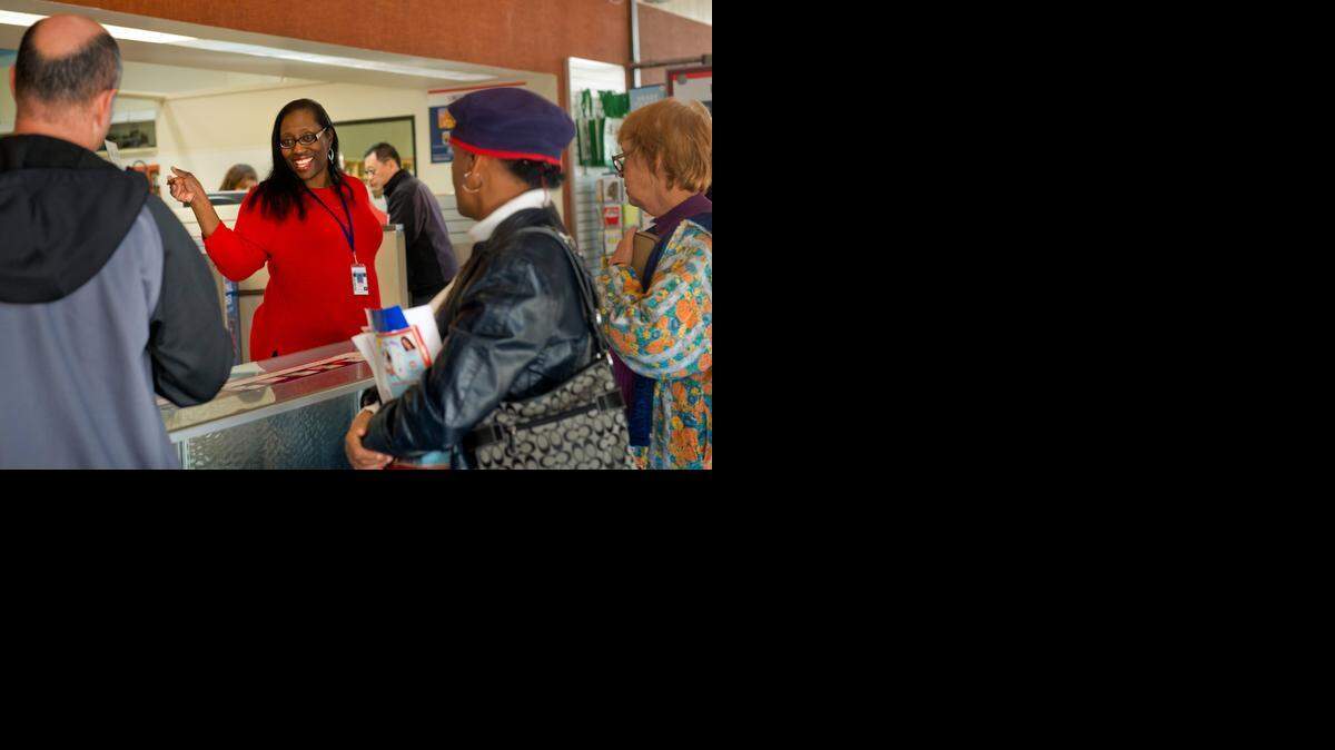 
Candace Cheathon, customer relations coordinator for the Sacramento district, answers questions for customers waiting in line at the Royal Oaks Post Office on Saturday. The post office is extending weekend hours through the holidays.
