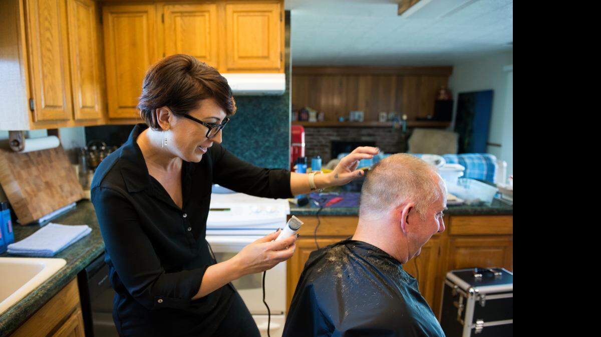 Elisa Stephens, former Campbell Soup worker, has started a mobile hairstyling business and gives a haircut to client at his home in Orangevale.