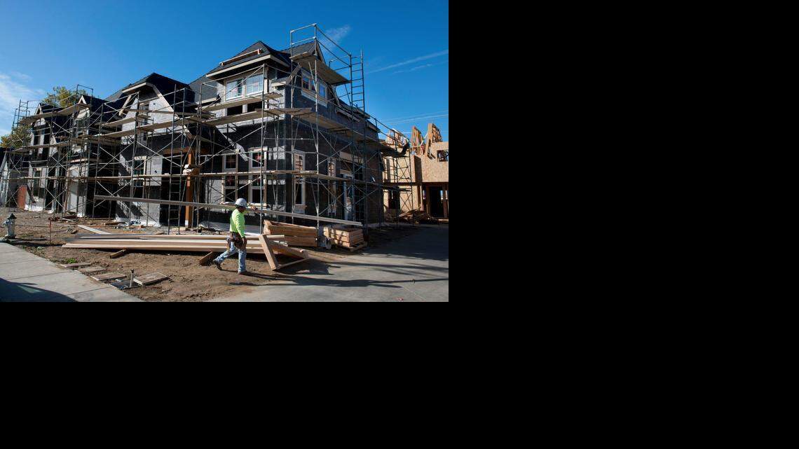 
A construction worker carries lumber outside new homes being built in the Curtis Park Village development just east of Sacramento City College on Tuesday in Sacramento.

