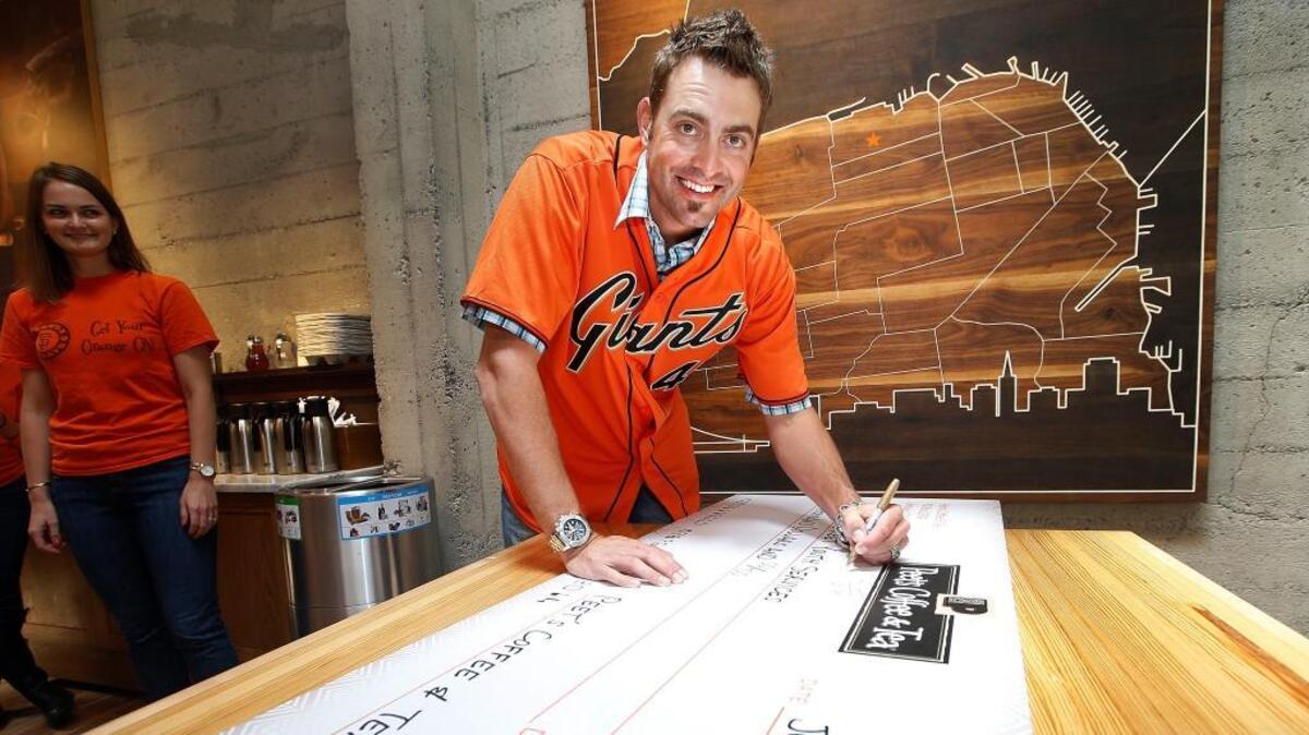 Giants pitcher Jeremy Affeldt signs a donation check at the flagship Peet’s Coffee & Tea store in 2014. The store is offering Black Friday deals.