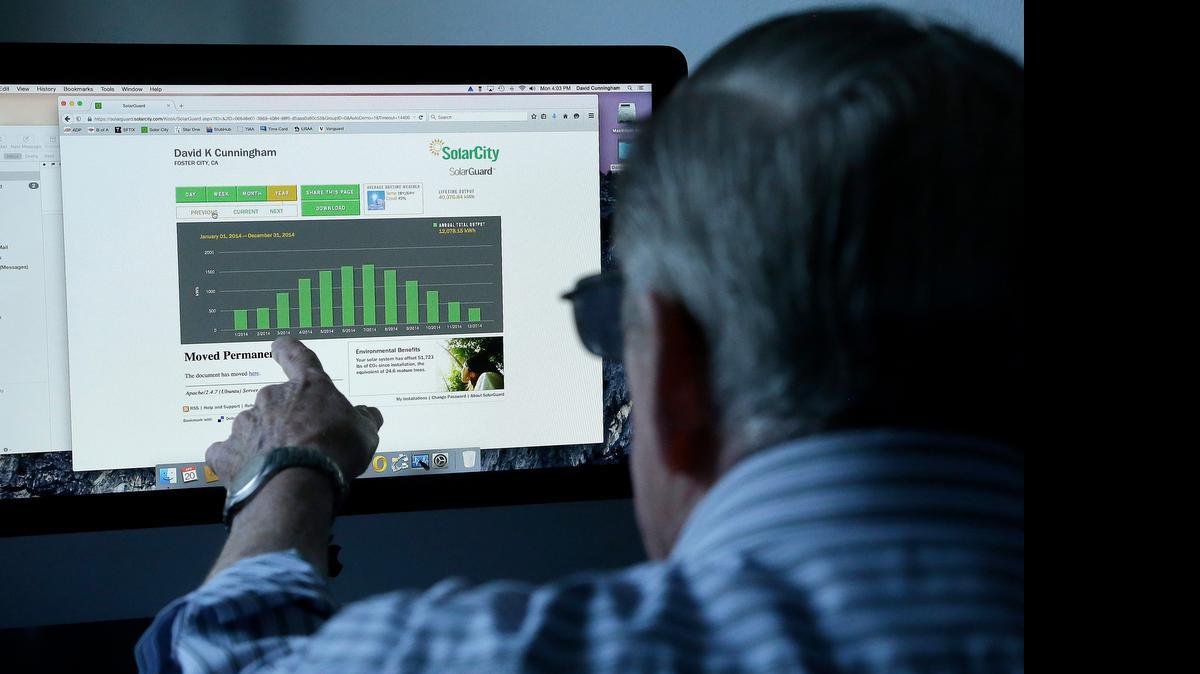 David Cunningham points toward his SolarCity Web page, which details the solar energy output at his home in Foster City.