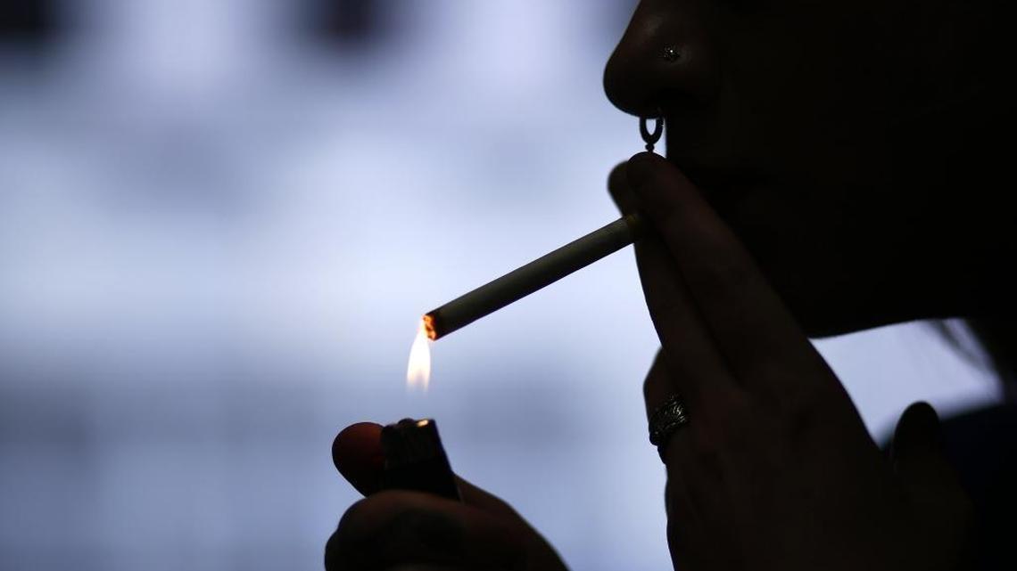 In this July 17, 2015 photo, store manager Stephanie Hunt lights a Marlboro cigarette while posing for photos at a Smoker Friendly shop in Pittsburgh.