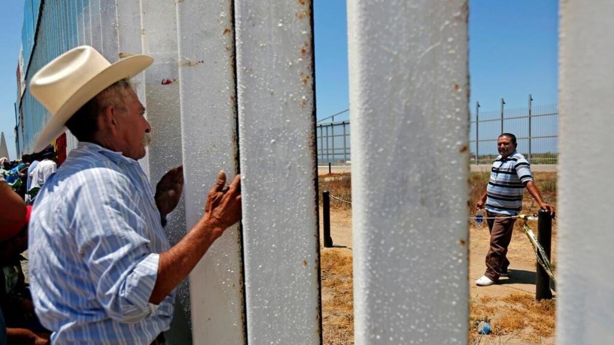Mauro Mejia, 63, of Nayarit, Mexico, peers through the fence from La Plaza de Faro, at the beach in Tijuana, to visit with his son Ricardo Mejia, 44, right, of Riverside, who he has not seen for 25 years, along the U.S.-Mexico border in Tijuana, Baja Calif. Every Saturday and Sunday, U.S. Border Patrol opens the secondary fence from 10 a.m. to 2 p.m. allowing family and friends to visit from Border Field State Park.