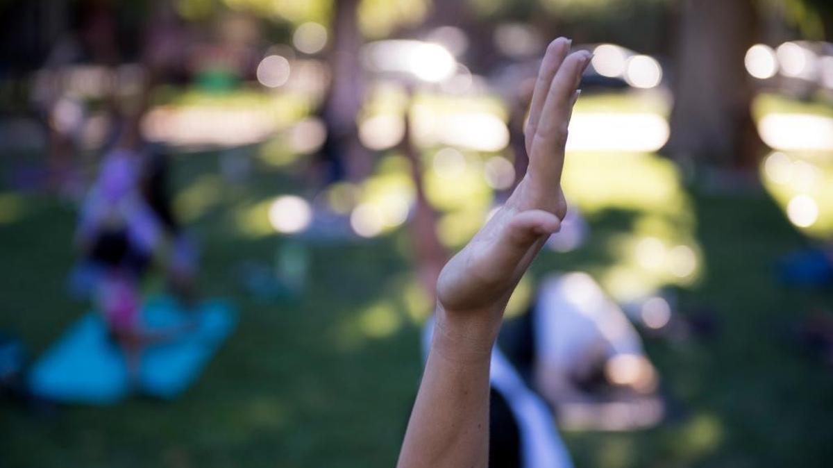 FILE -- A woman extends her arm into the air at Yoga in Park at Fremont Park on Thursday, July 20, 2017.