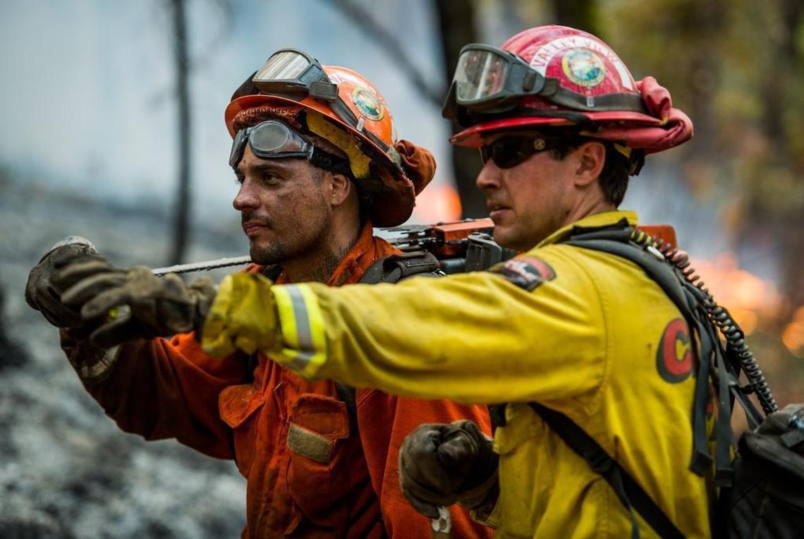 A Cal Fire crew member from Santa Barbara and an inmate firefighter inspect a spot fire fire near the town of Glencoe on Highway 26 on Friday, Sept. 11, 2015. The Butte fire has burned over 64,728 acres and is forcing evacuations in the dry hills east of Highway 49.