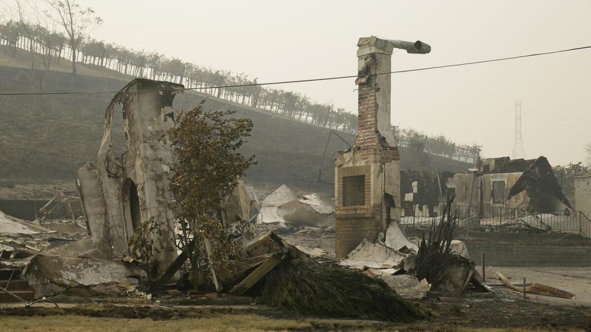 The remains of a burned building at the Clover Stornetta dairy are seen below vineyards on Tuesday in Sonoma. Workers in Northern California's renowned wine country picked through charred debris and weighed what to do with pricey grapes after wildfires swept through lush vineyards and destroyed at least two wineries and damaged many others.