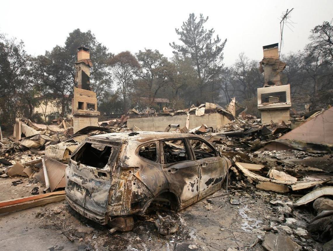 The burned remains of a car sits in the driveway of a home near the Silverado Country Club and Resort on Tuesday in Napa. Wildfires whipped by powerful winds swept through Northern California sent residents on a headlong flight to safety through smoke and flames as homes burned.