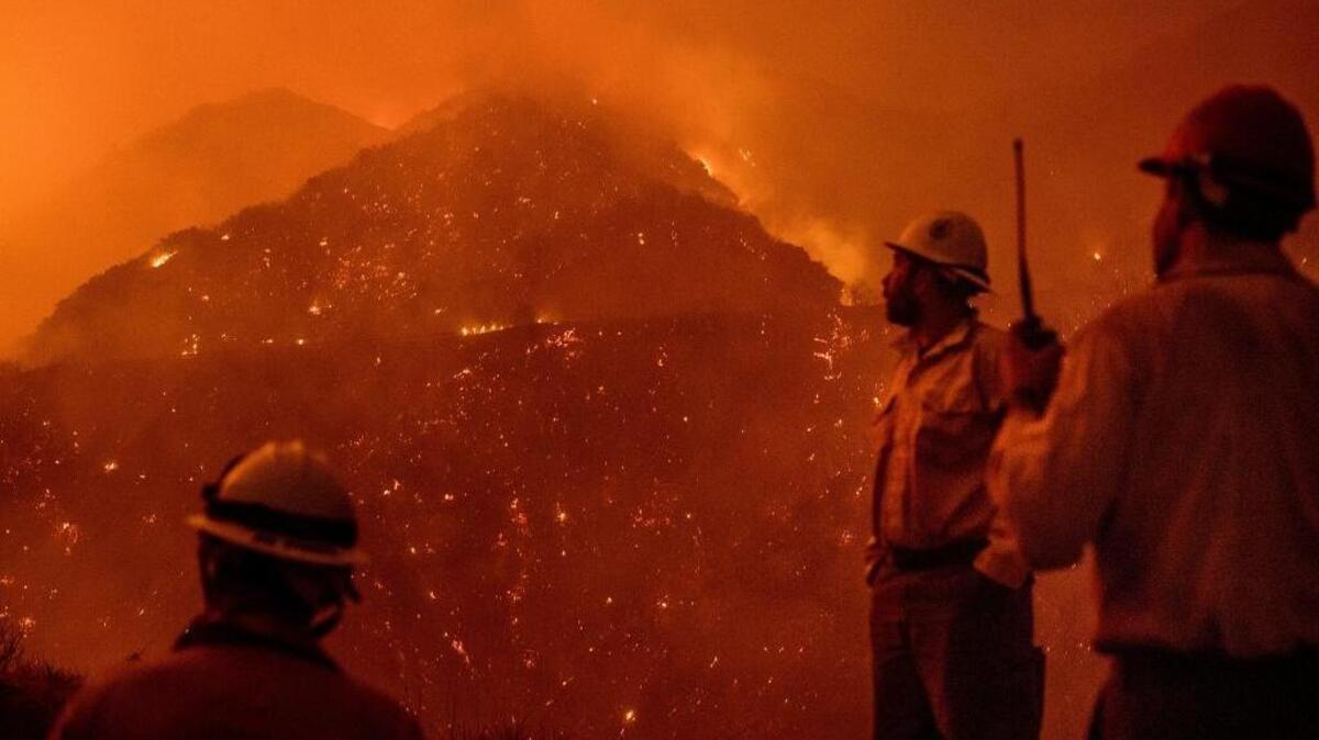 FILE - In this Dec. 8, 2017, file photo, firefighters monitor the Thomas Fire as it burns through Los Padres National Forest near Ojai, Calif.