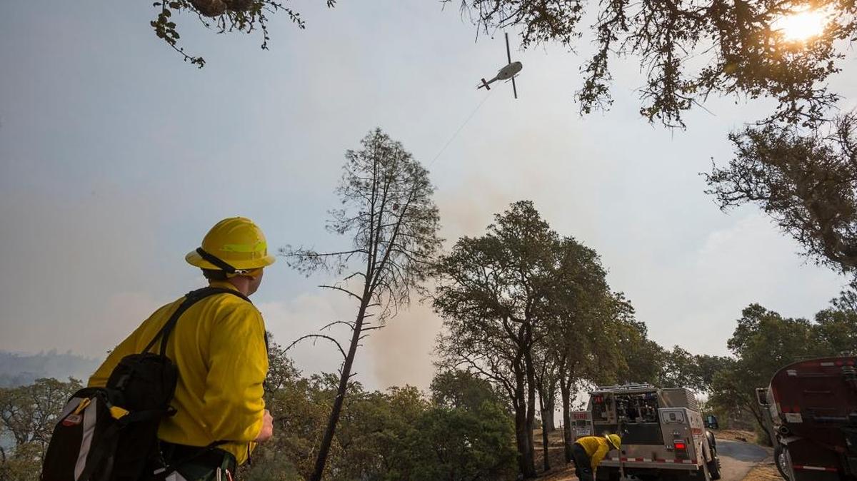 NPS firefighter, Chris Corder, watches a helicopter drops water on the Pocket Fire as it approaches homes in the Vineyard Development in Sonoma County outside of Geyserville on Wednesday October 11, 2017.
