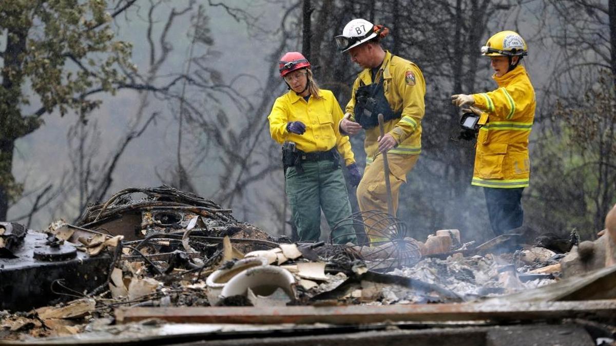 
Firefighter Sean Norman, center, and search dog handlers Mary Cablk, left, and Lynne Engelbert look over the remains of a home in the Anderson Springs area of a man missing following a wildfire days earlier Wednesday, near Middletown. Aided by drought, the flames have consumed more than 109 square miles since the fire sped Saturday through rural Lake County. Cooler weather helped crews gain ground and the fire was 30 percent contained Wednesday. 
