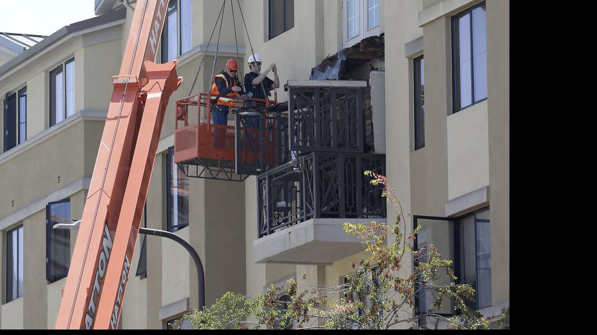 
Workers look at a fourth-floor balcony railing as it rests on the balcony below at the Library Gardens apartment complex in Berkele on Tuesday. 
