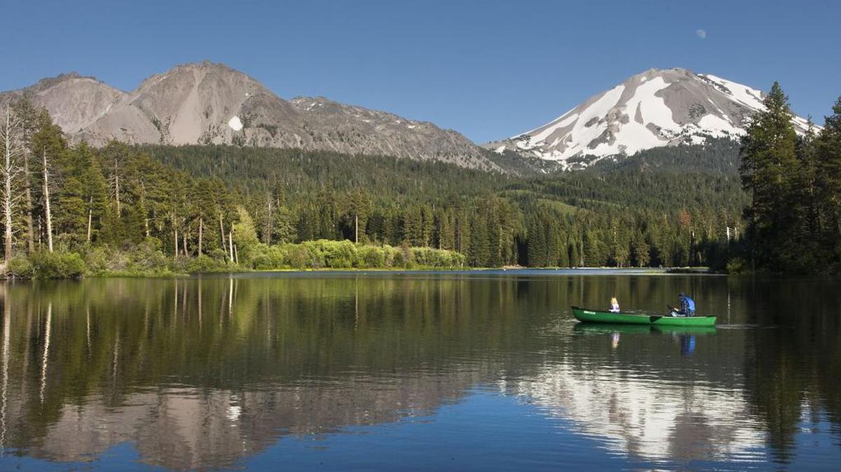 
Chaos Crags, top left, and Lassen Peak (with snow) loom over the occupants of a canoe on Manzanita Lake in Lassen Volcanic National Park on Friday, July 7, 2006.  
