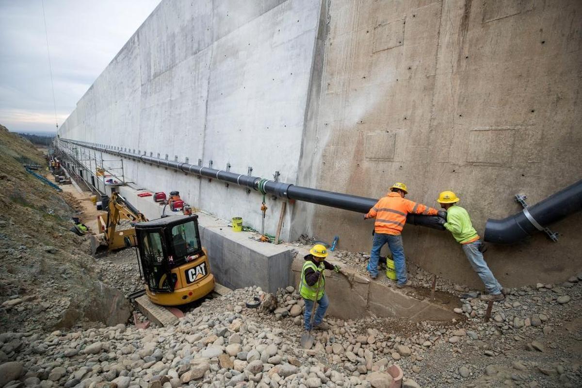 Kiewit Corp. workers connect drain pipes to the outer sidewalls of the upper chute of the main Oroville Dam spillway in December 2017. The spillway, rebuilt at a cost of $1.1 billion, could be used for the first time in early April.