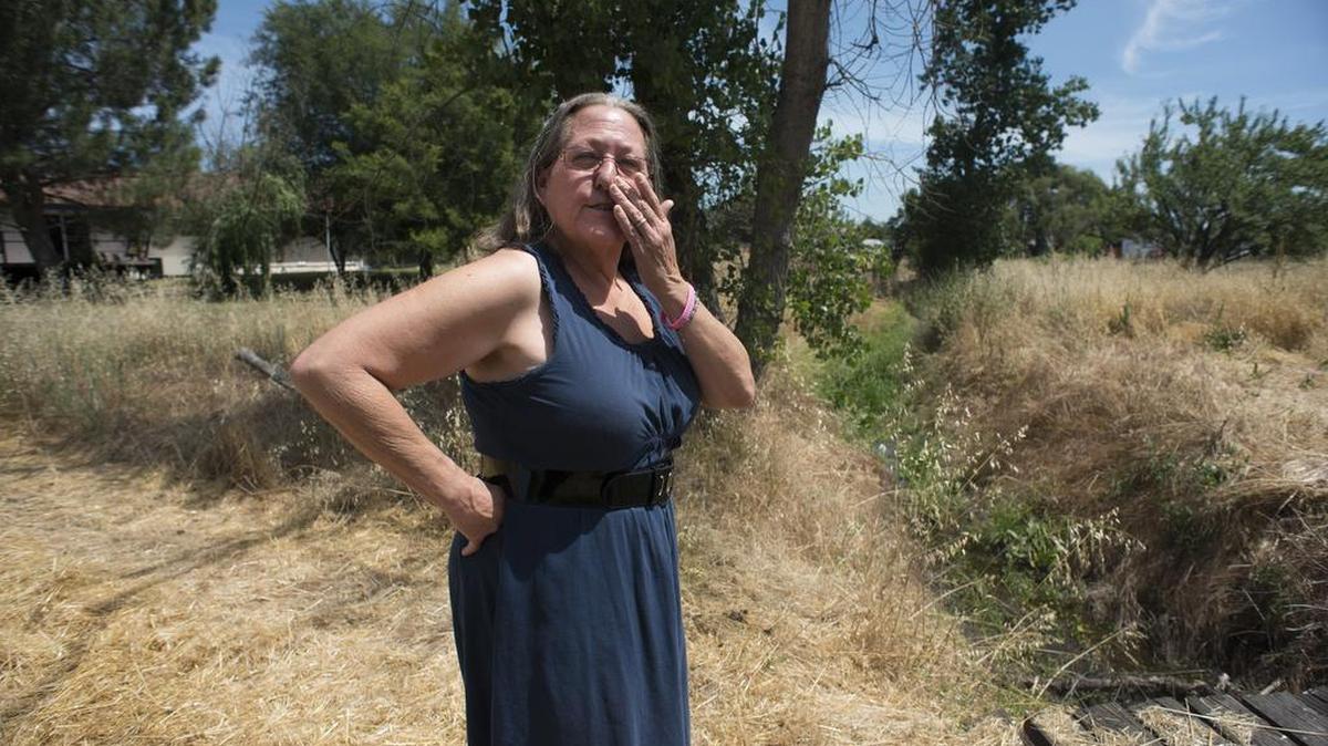 Anna Marie Tomlinson, of Rio Linda, buys bottled drinking water for herself and her family because the water on her property was tested to have high chromium and arsenic levels. Here she stands by a contaminated creek behind her home.