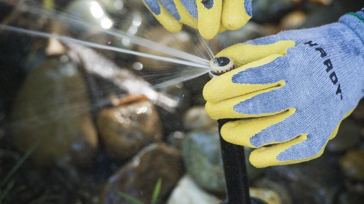 A worker adjusts a sprinkler at a Sacramento home last June.
