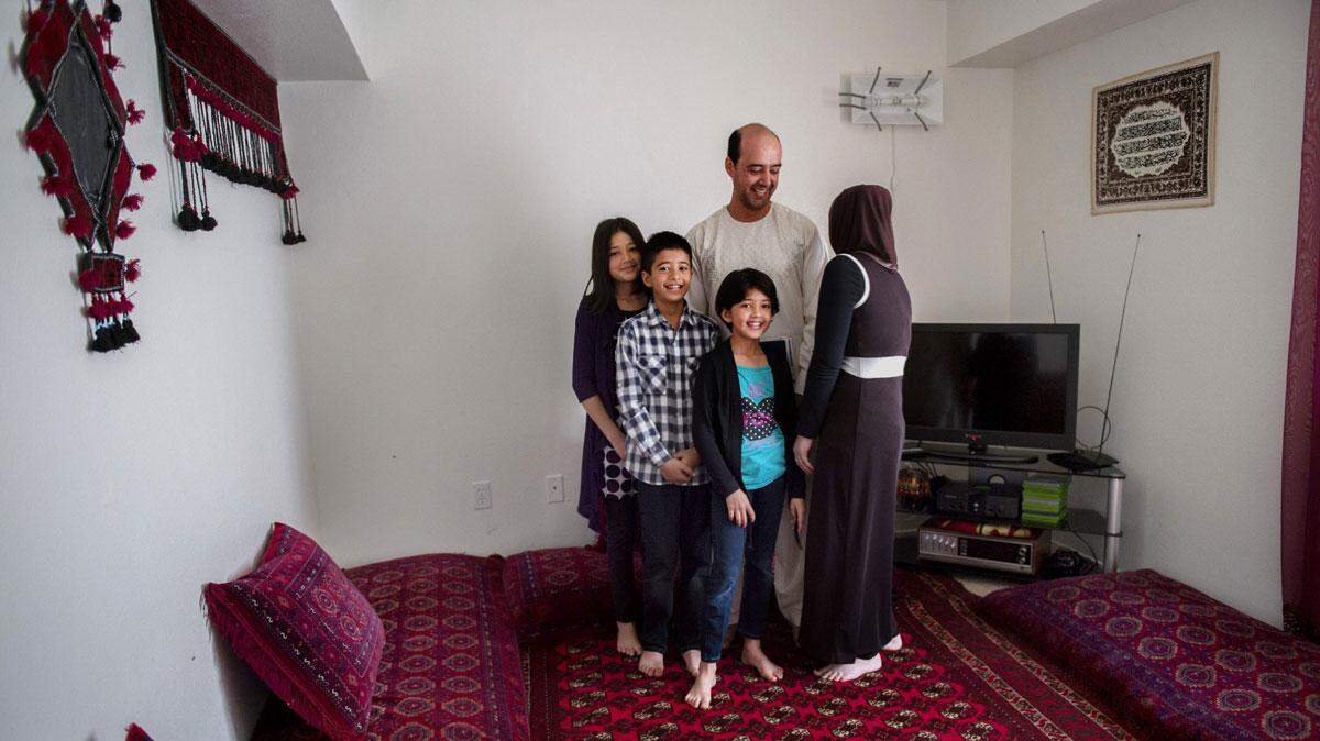 Dr. Fahim Pirzada, 39, is who Afghan refugees call for help, while establishing his  life in a new land. In his Sacramento home, Pirzada’s wife Suman, 34, right, turns away because she does not want her face photographed for a portrait with their children, from left, Maryam, 12, Zakariya, 11, and Bahar, 7. Outside his home, he works as a medical interpreter – he was a doctor in Afghanistan. He also heads VIRTIS – the nonprofit Veteran, Immigrant and Refugee Trauma Institute of Sacramento – which provides mental health care to refugees.